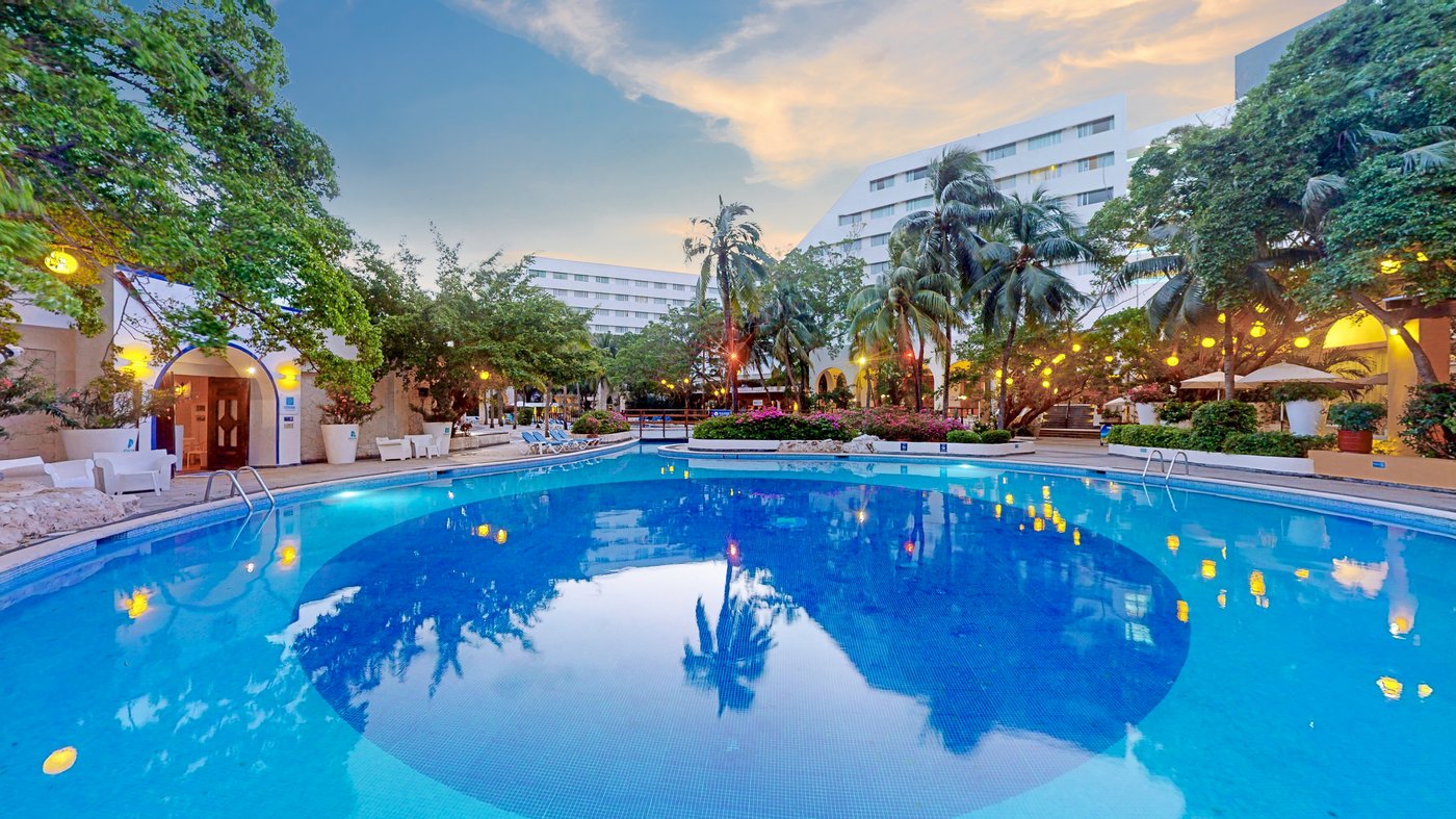 View of a pool at the hotel Grand Oasis Palm with a bridge and cabanas.