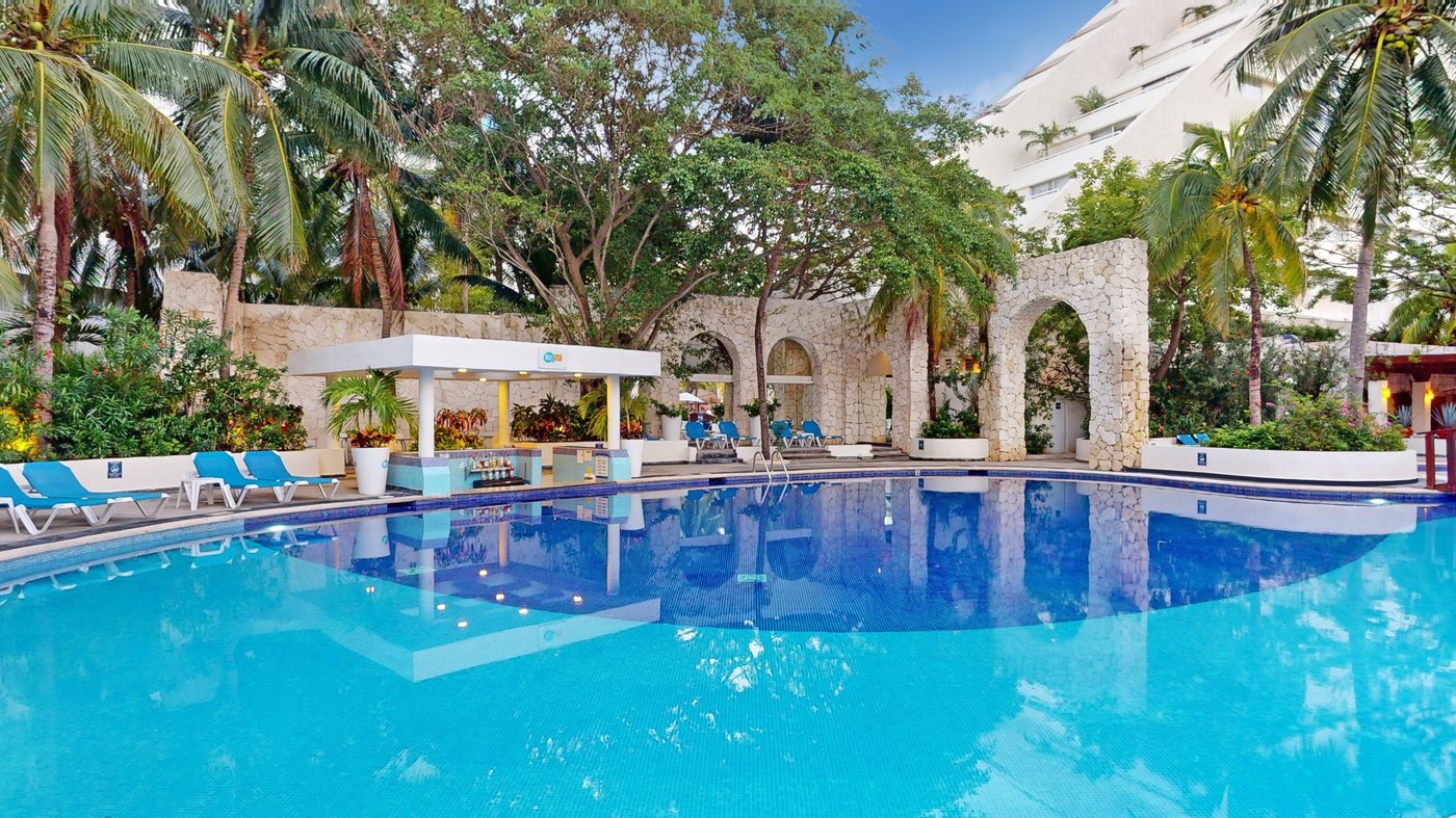 Grand Oasis Palm hotel pool with sunbeds and umbrellas.