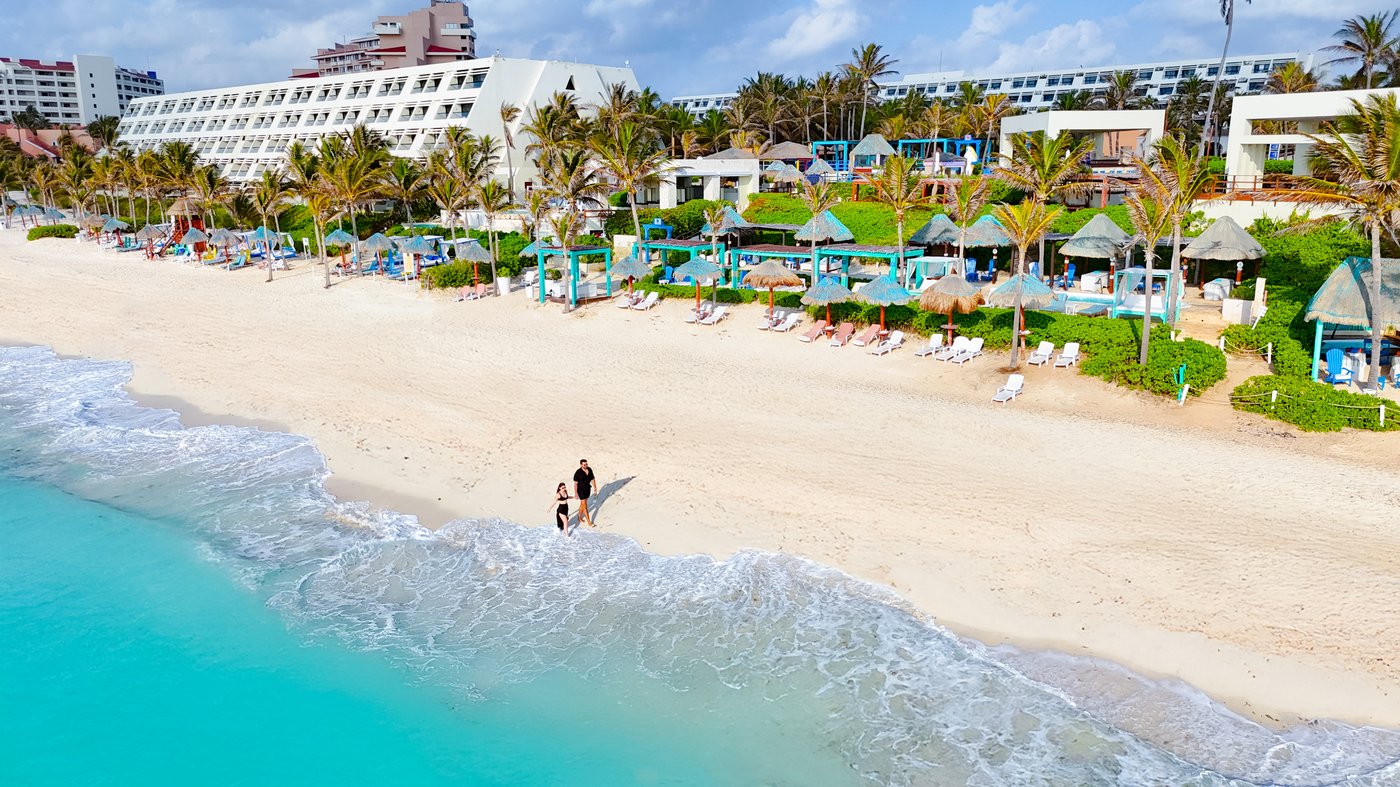 Galeria de Praia: Vista da praia com camastros e palmeras no hotel Grand Oasis Cancun.