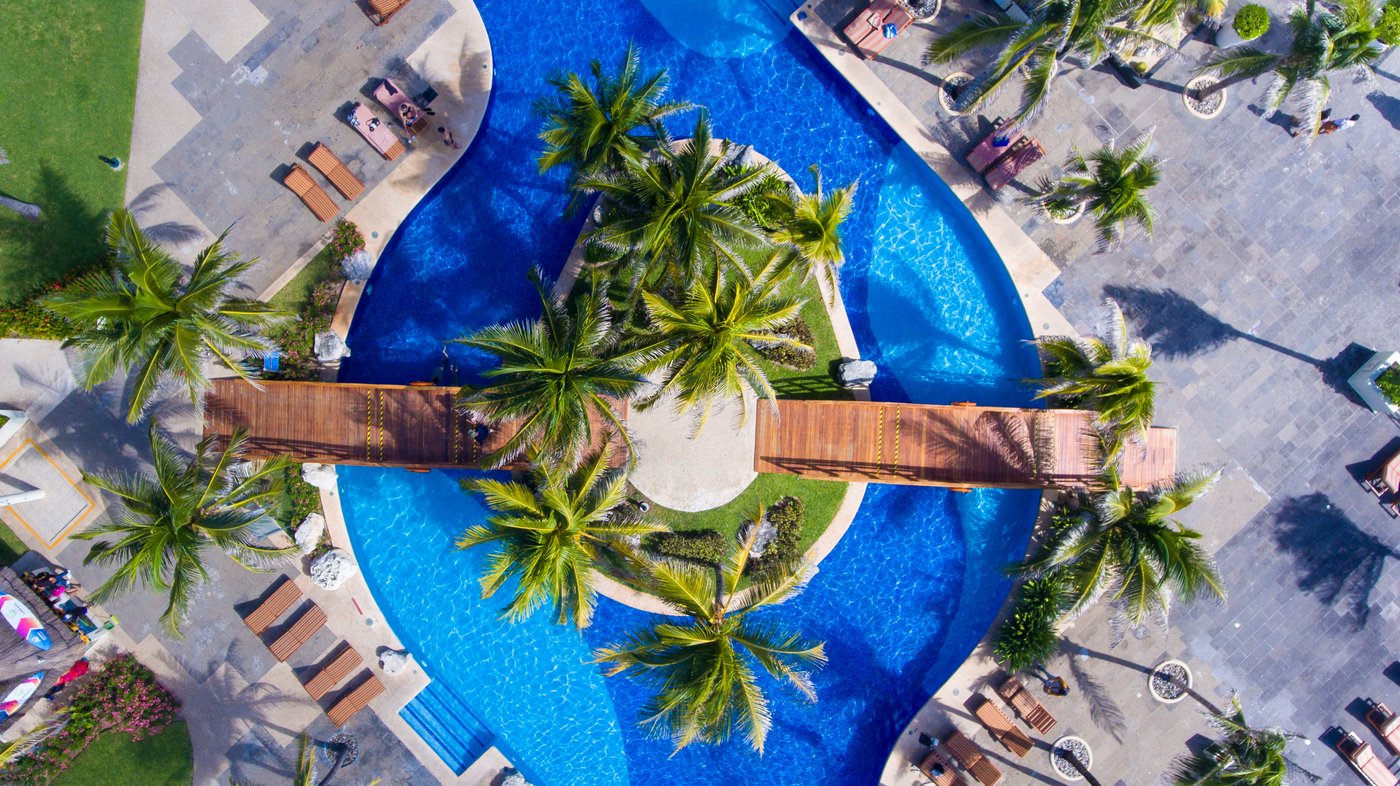 Galeria: Vista aérea de una de las piscinas do hotel The Pyramid Cancun, com palmeras e camastros.