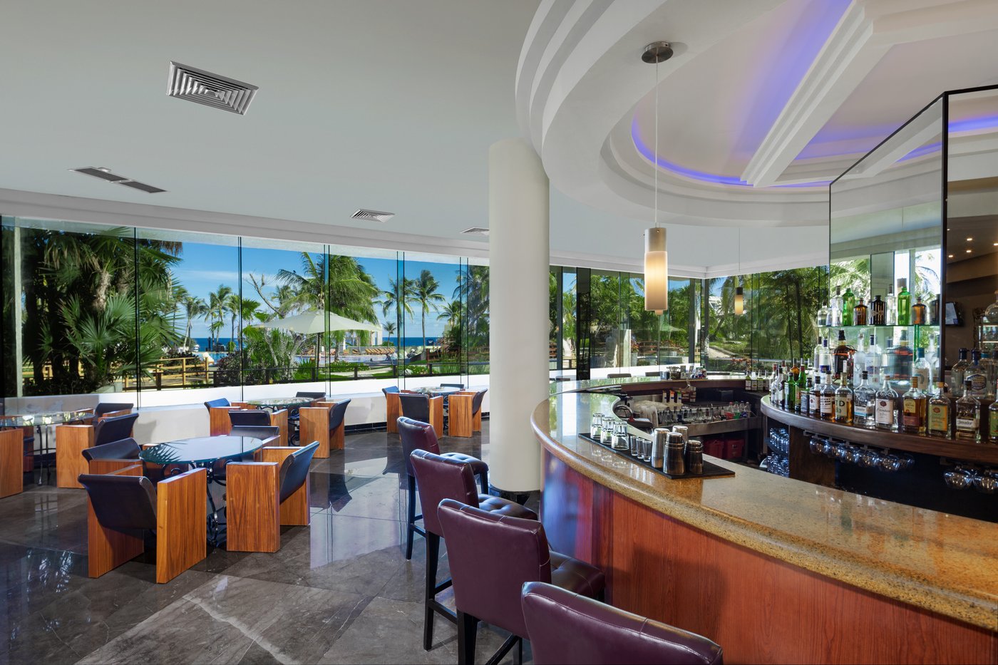 Galeria: Una barra de bar circular com sillas rojas no hotel The Pyramid Cancun.