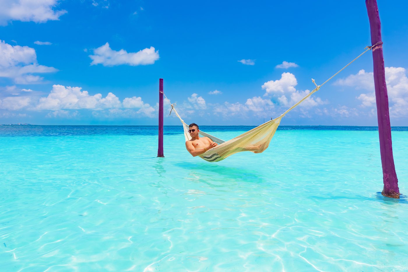 Huésped relajándose en una hamaca sobre el agua no hotel The Sens Cancun.