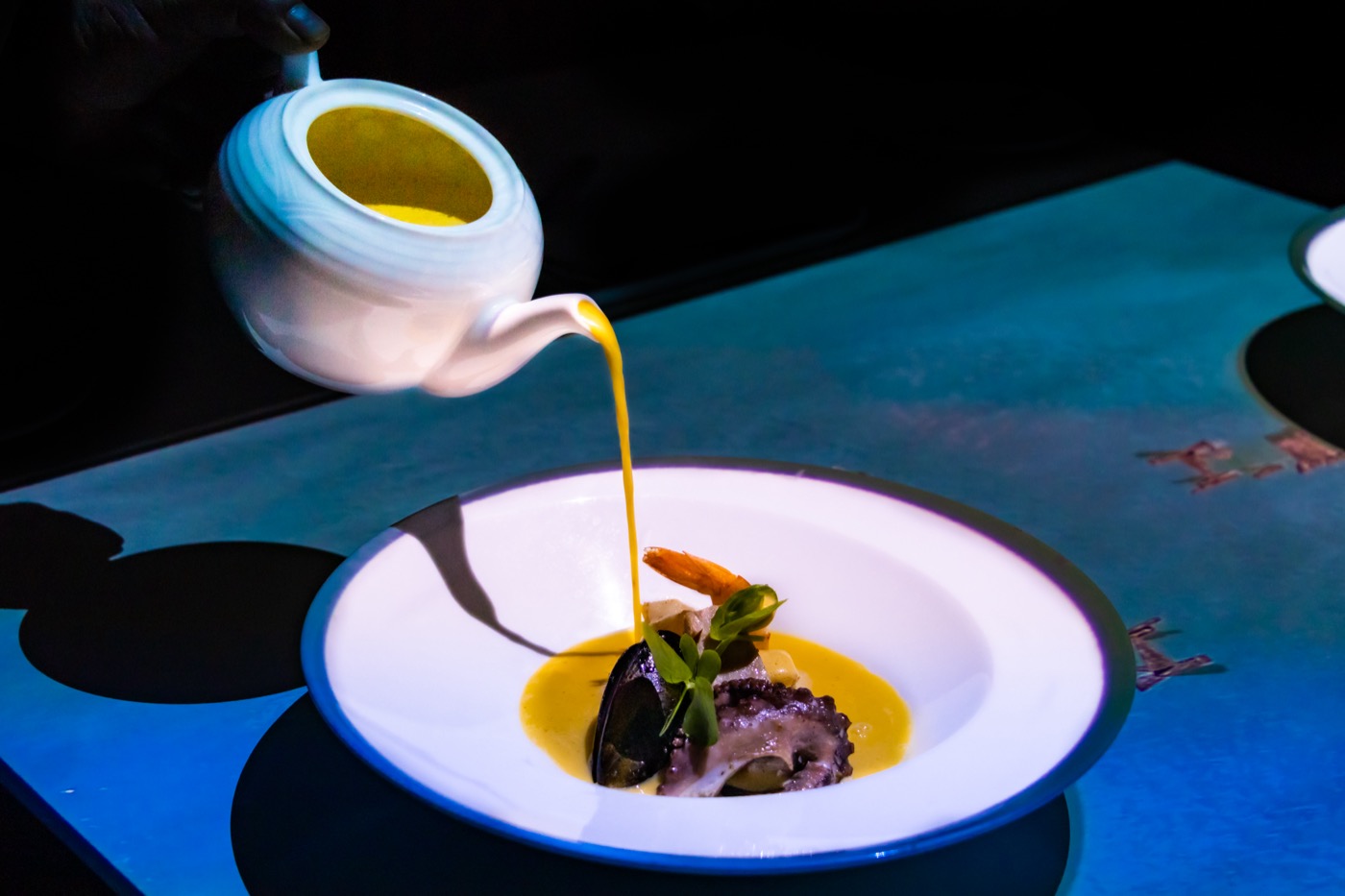 Galeria de A&B: Mano sirviendo salsa sobre un plato no hotel The Sens Tulum Riviera.